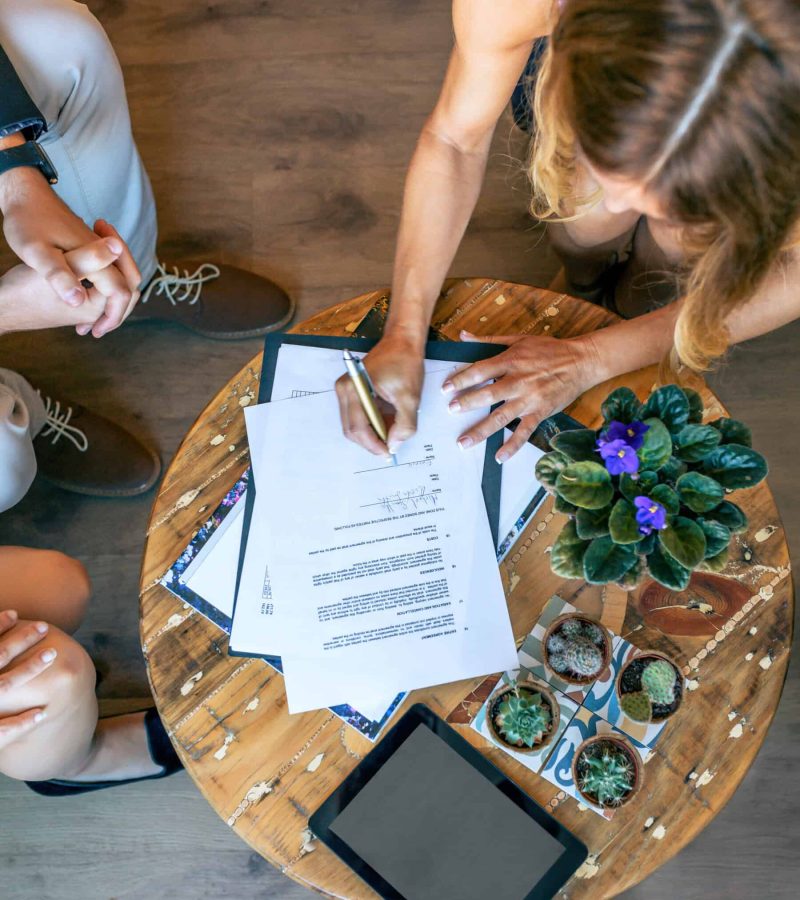 Top view of woman signing a document at an informal work meeting